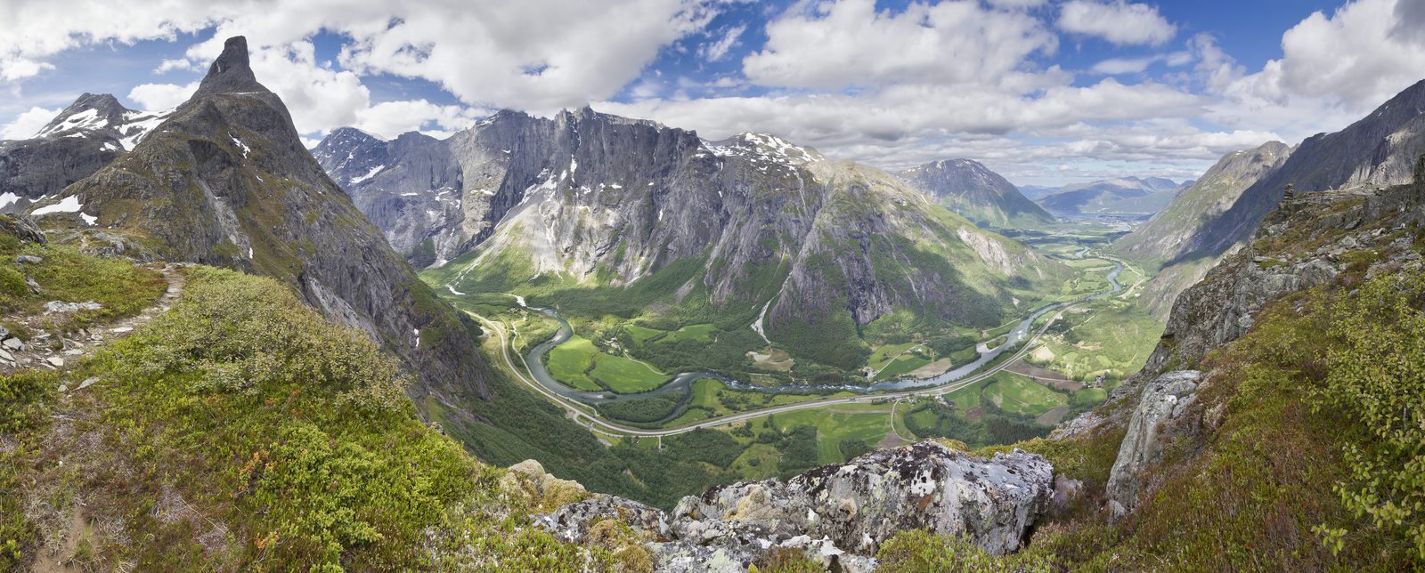 Klatrere i sele og hjelm henger i stålvaier på Nesakslas vestvegg over Åndalsnes og Romsdalsfjorden