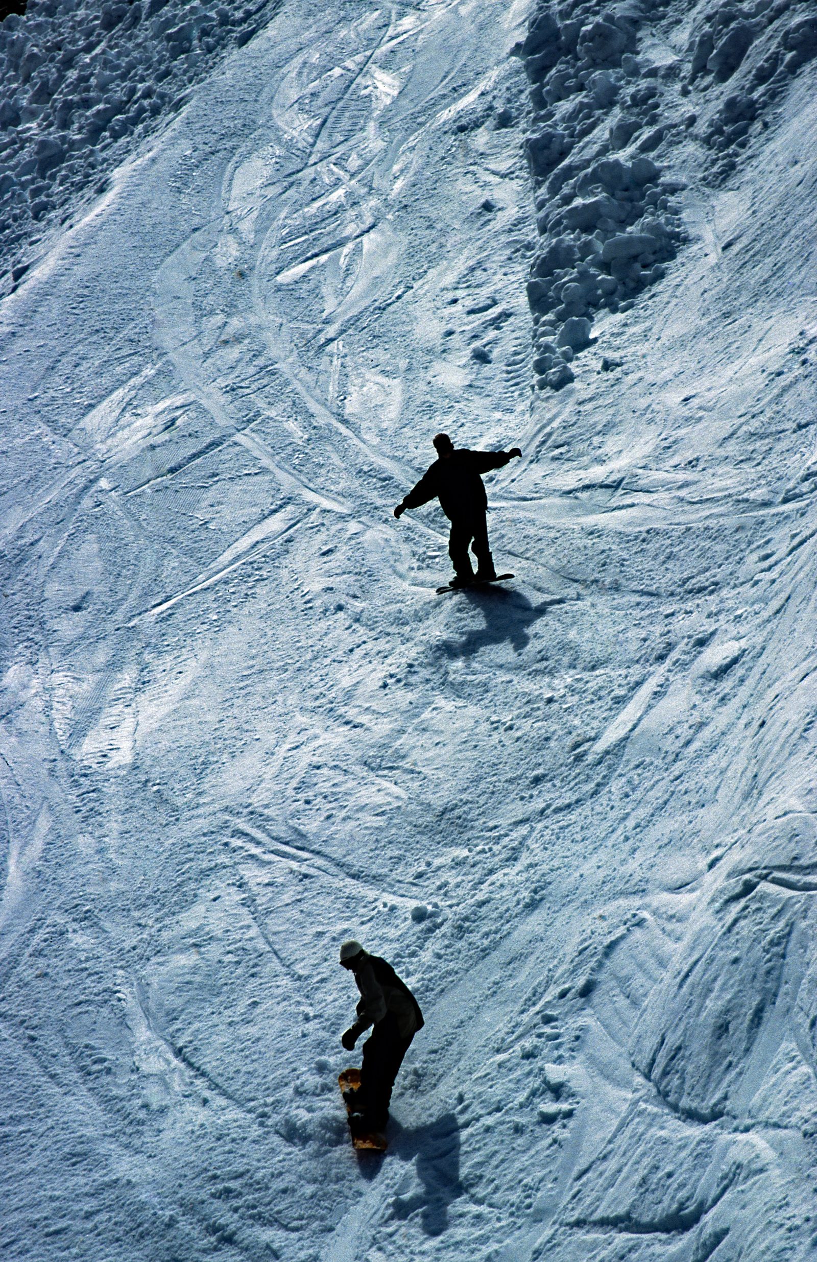 Skiløpere i nedfarten ved Stryn Sommerski på Tystigbreen, med snødekt fjellandskap i bakgrunnen