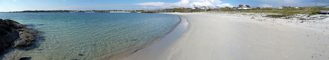 Åkrasanden med lang lys sandstrand som strekker seg mot havet ved Åkrehamn på Karmøy
