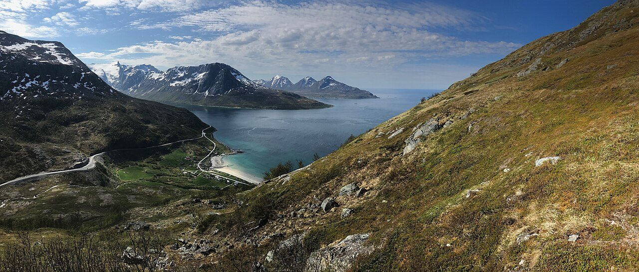 Den hvite sandstranden i Grøtfjord på yttersiden av Kvaløya, omkranset av bratte fjell