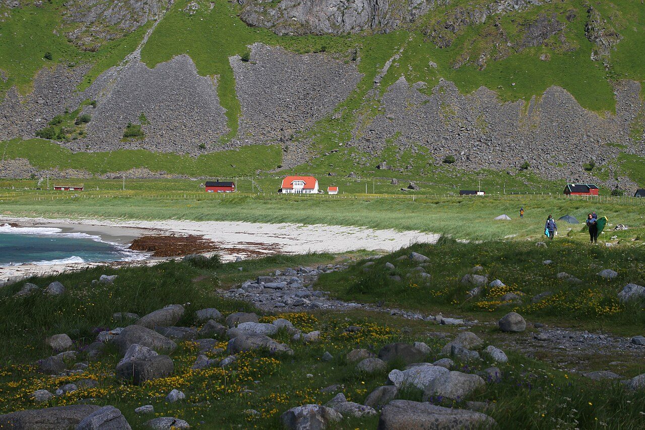 Oversiktsbilde av Unstadbukta med sandstrand, bygd og fjell i Vestvågøy, Lofoten