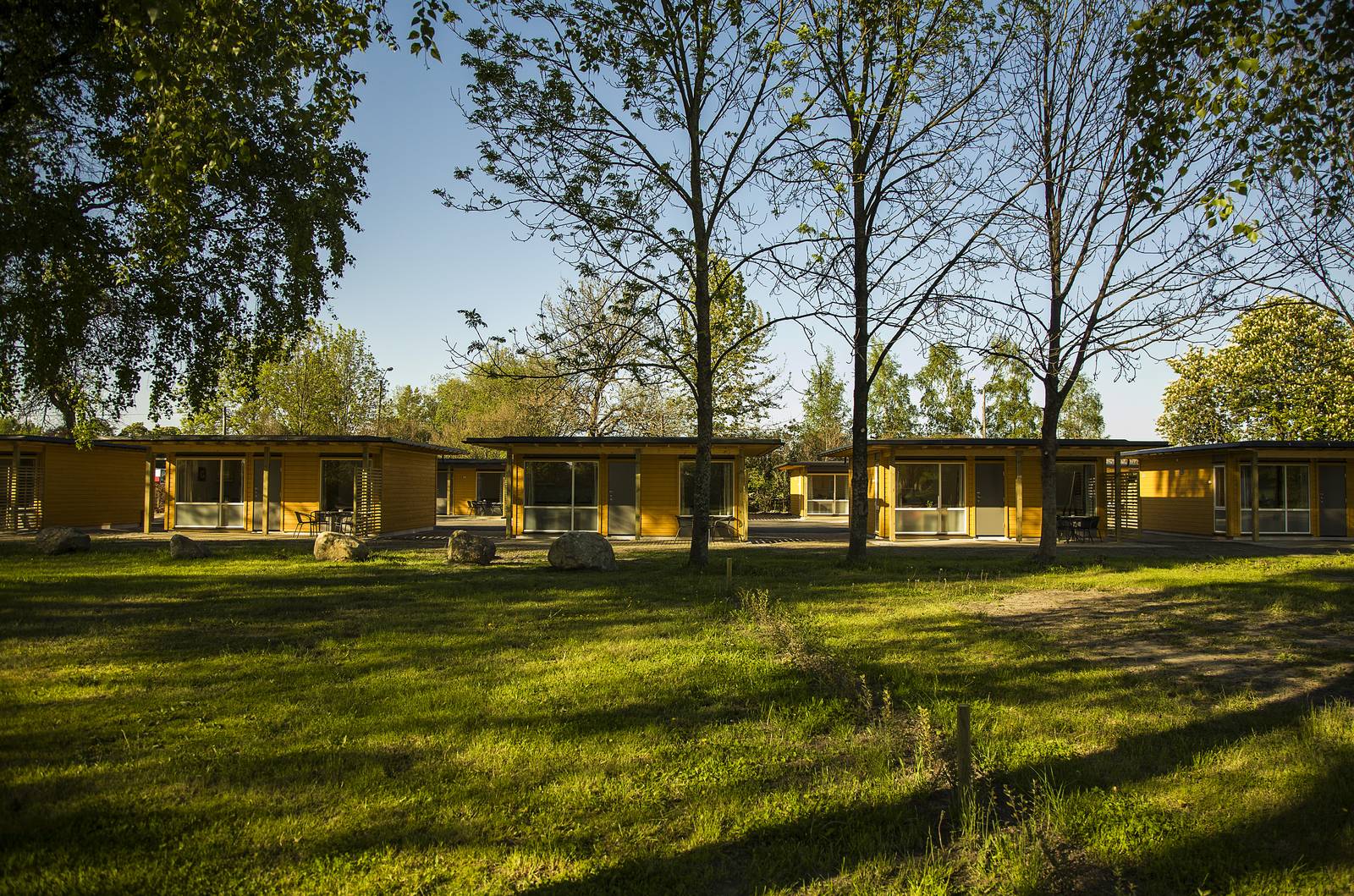 Gelbe Motel- und Hüttengebäude auf Aktivitetsbyen Gamle Fredrikstad, umgeben von Rasen und Bäumen