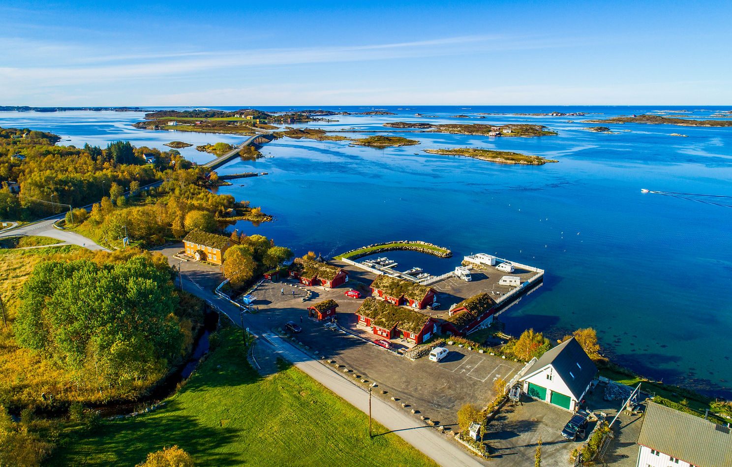 Sjøstuer i tre ved sjøkanten på Kårvåg, Averøy, med Atlanterhavsveien i bakgrunnen