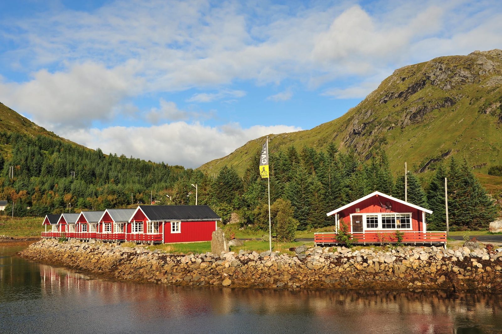 Sjøhytter ved strandkanten på Brustranda Fjordcamping med utsikt over fjorden og Lofotfjellene i Valberg
