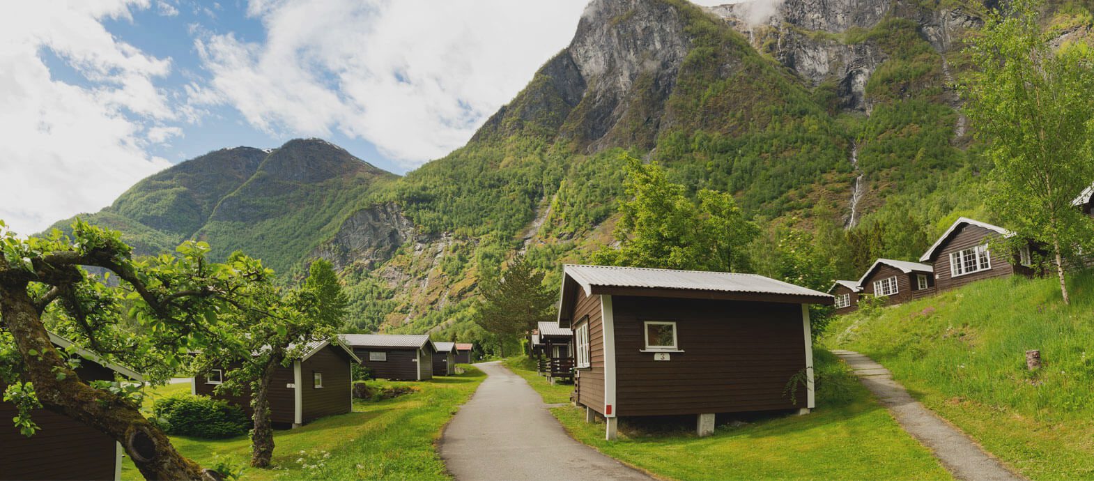Terrasserte oppstillingsplasser i eplehage med fjell rundt på Flåm Camping og Vandrarheim