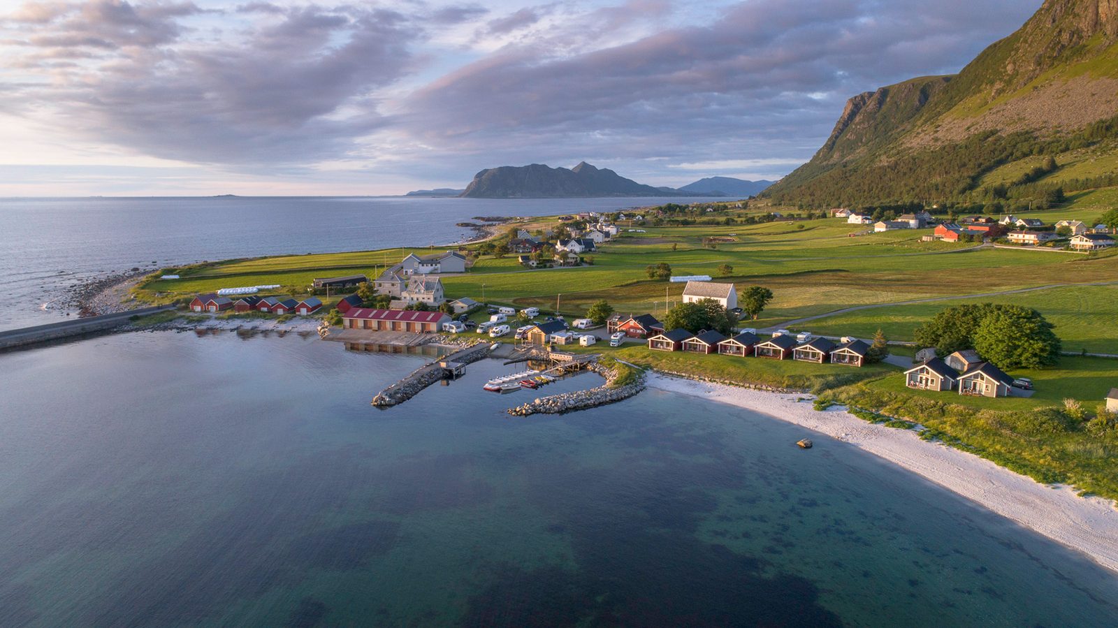 Hvit sandstrand og hytter ved Flø Feriesenter på Sunnmørskysten en sommerdag
