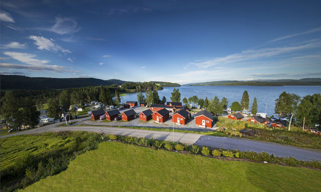 Føllingstua Camping ved sørenden av Snåsavatnet med campingvogner, bobiler og hytter i strandnær furuskog