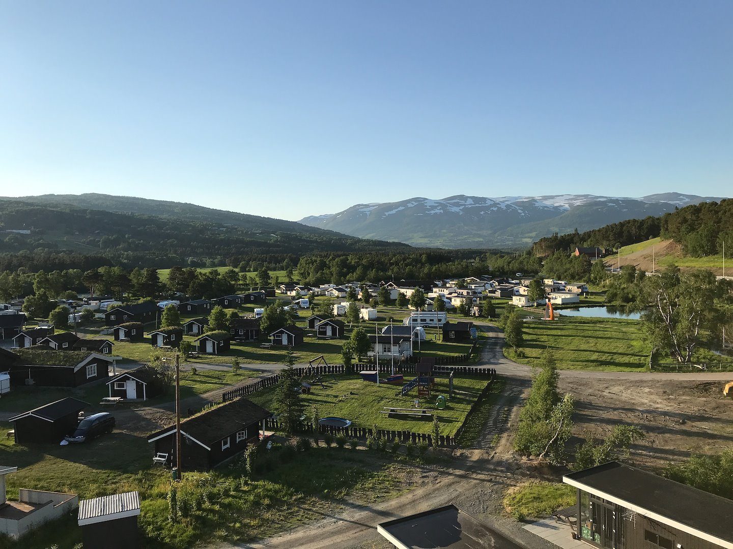 Granmo Camping ved elva Driva sør for Oppdal med campingvogner, bobiler og hytter omgitt av fjell