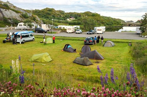 Tømmerhytte og bobilplasser ved Kabelvåg Feriehus og Camping med Lofotfjellene i bakgrunnen