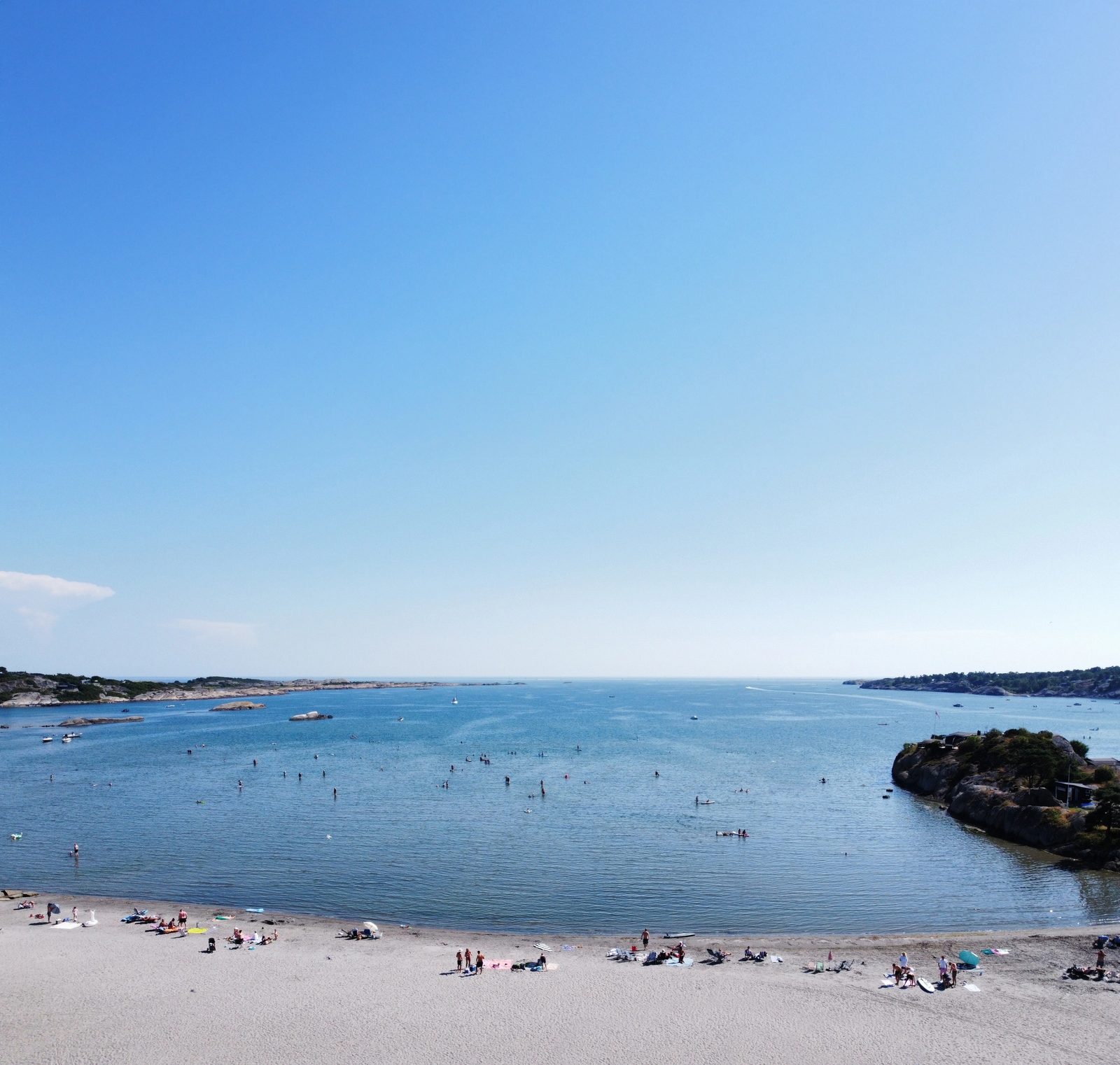 Bobiler og campingvogner på romslige plasser ved sandstranden på Kolbensrød Camping i Naverfjorden