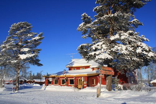 Bobiler og campingvogner på Kvanhøgd Turistsenter med snødekt Golsfjell-landskap i bakgrunnen.