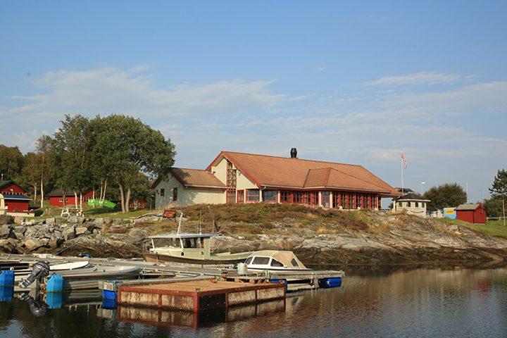 Lanternen marina og bygningsanlegg i Tjørvåg i Herøy, med båter ved gjestebrygga og kafé i bakgrunnen.