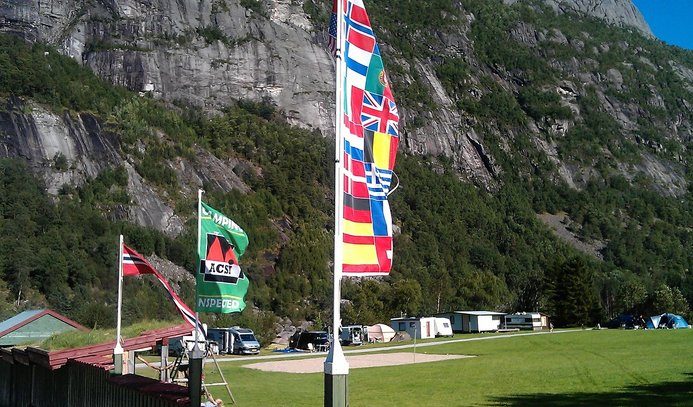 Lindeland Camping ved Sira-elven i Sirdal, med campingvogner og telt plassert i grønne naturomgivelser