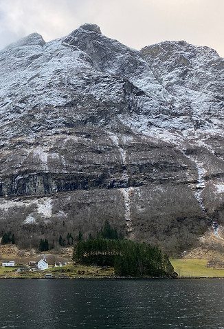 Gardstunet på Dyrdal Gard med Nærøyfjorden og bratte fjellsider i bakgrunnen
