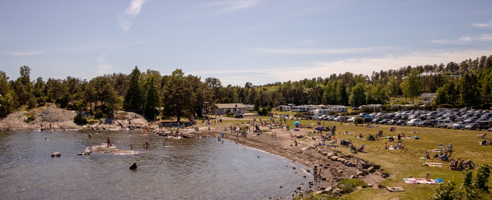 Sandstrand og badebukt med camping i bakgrunnen ved Nøtterøy Familiecamping Fjærholmen