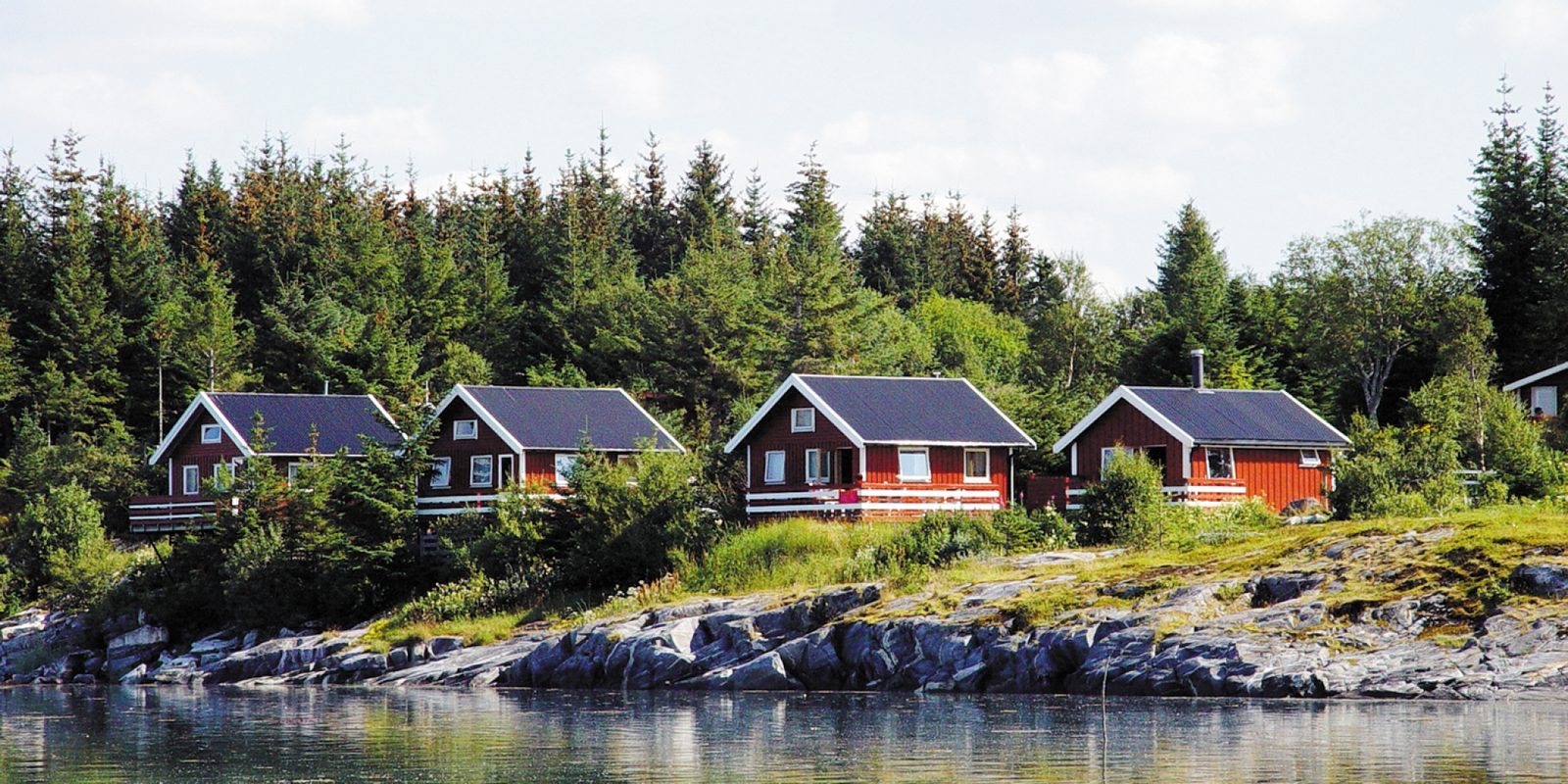 Sjøhytter og bobilplasser på Offersøy Camping med Helgelandskysten og De syv søstre i bakgrunnen