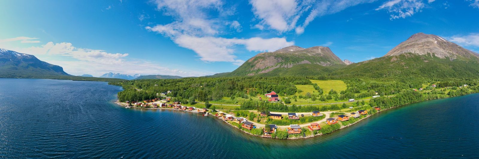 Oksfjord Familiecamping ved vannkanten av Oksfjordvannet med Kvænangsfjellet i bakgrunnen