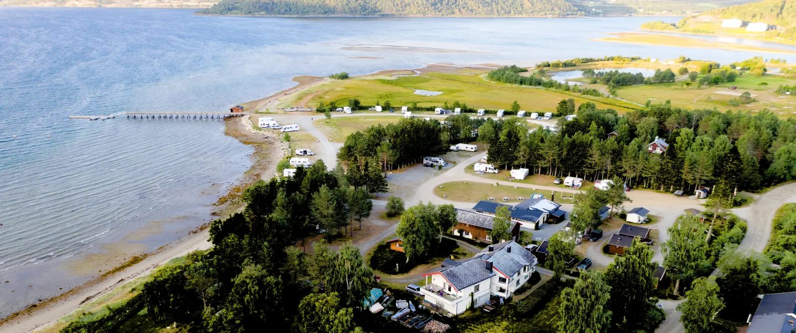 Bobiler og campingvogner på Rognan Fjordcamp med utsikt mot Saltdalsfjorden