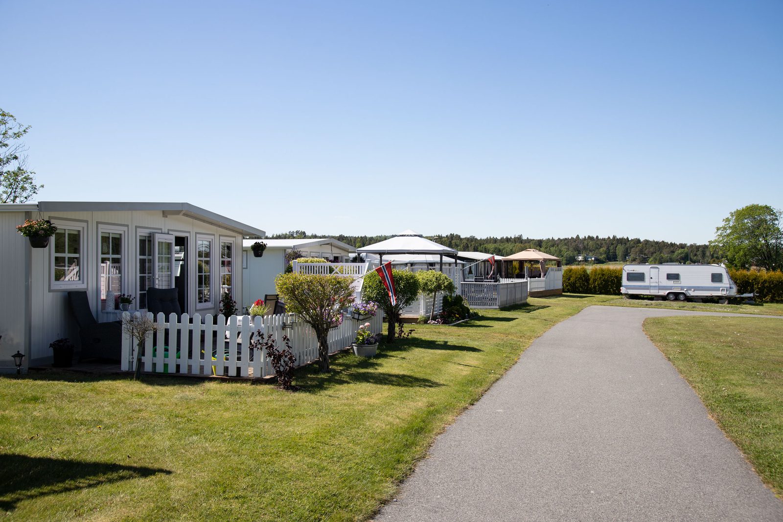 Bobiler og campingvogner på gressbakker ved sandstrand og svaberg innerst i Rognsfjorden, Stathelle