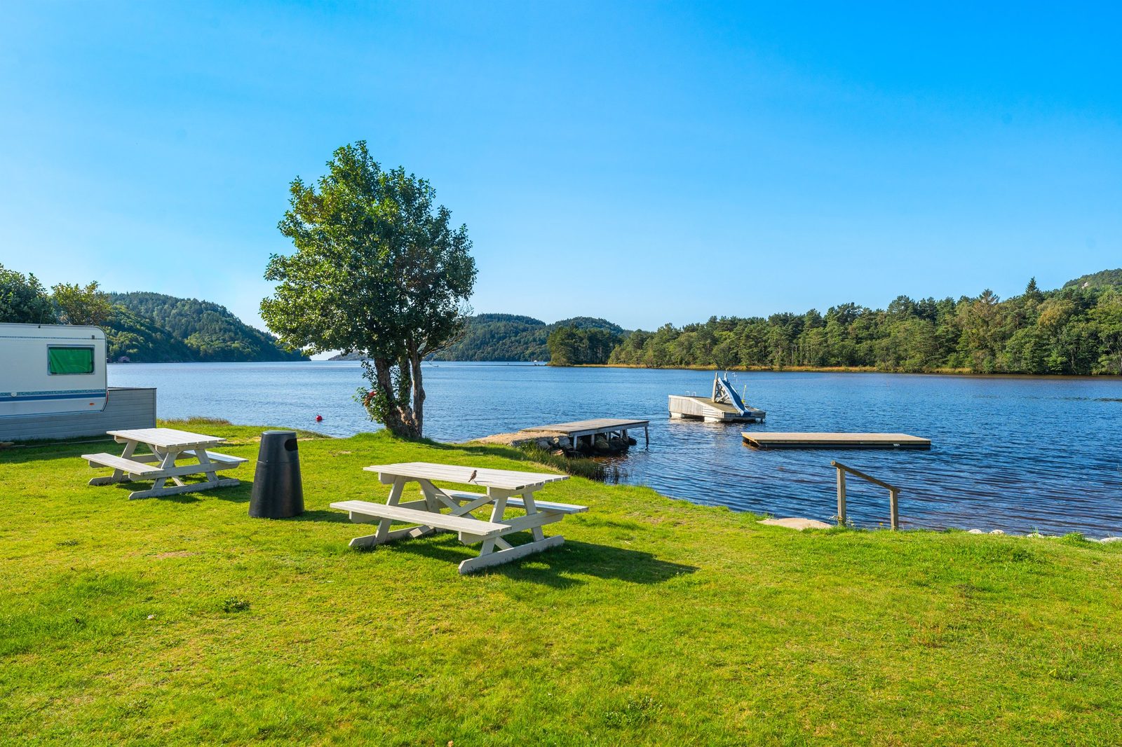 Solstrand Camping ved Audnaelva i Lindesnes med badestrand, flytebrygge og campingvogner i sommerlandskap