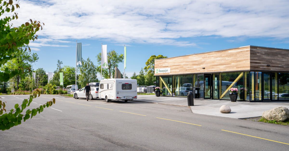 Bobiler og campingvogner på Topcamp Bogstad med Bogstadvannet og skogkledde åser i bakgrunnen