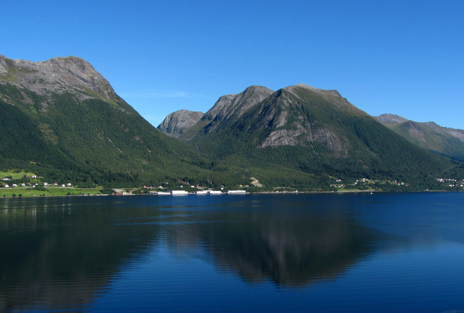 Brennevinsgrova microdestilleri på gården Lillebø innerst i Sykkylvsfjorden, omgitt av Sunnmørsalpane