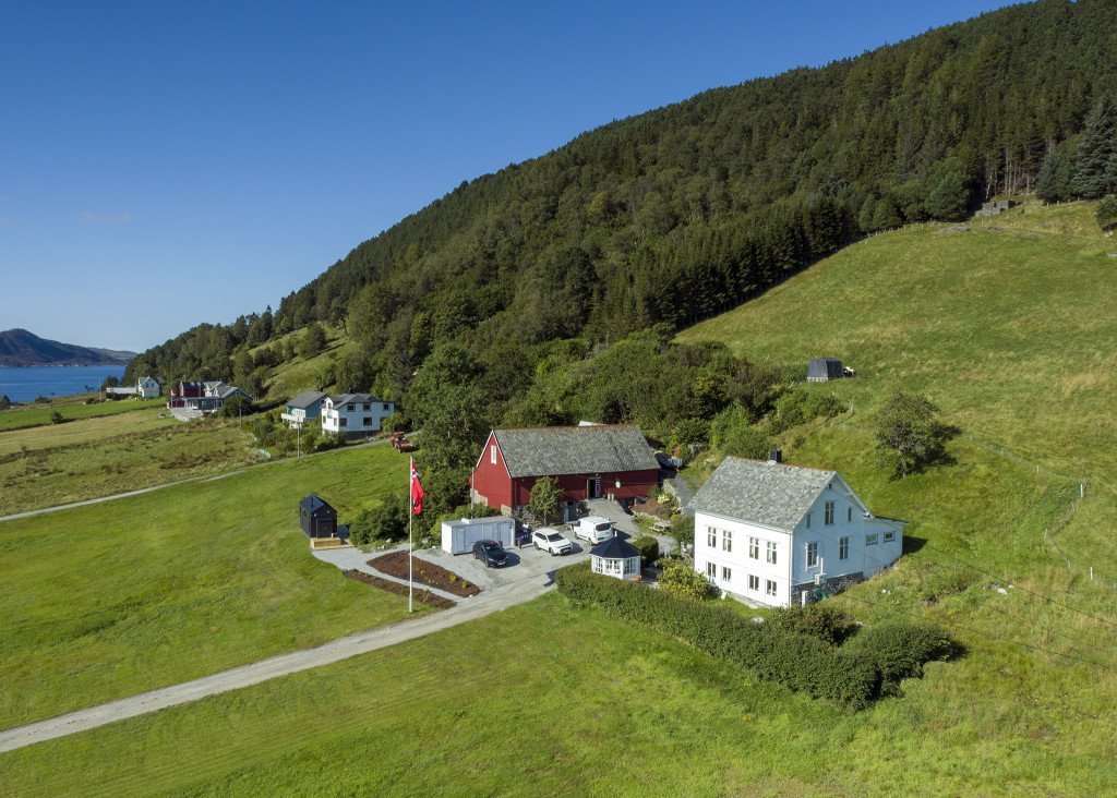 Gårdstunet på Kråen Gard med utsikt mot fjord og fjell i Larsnes, Møre og Romsdal