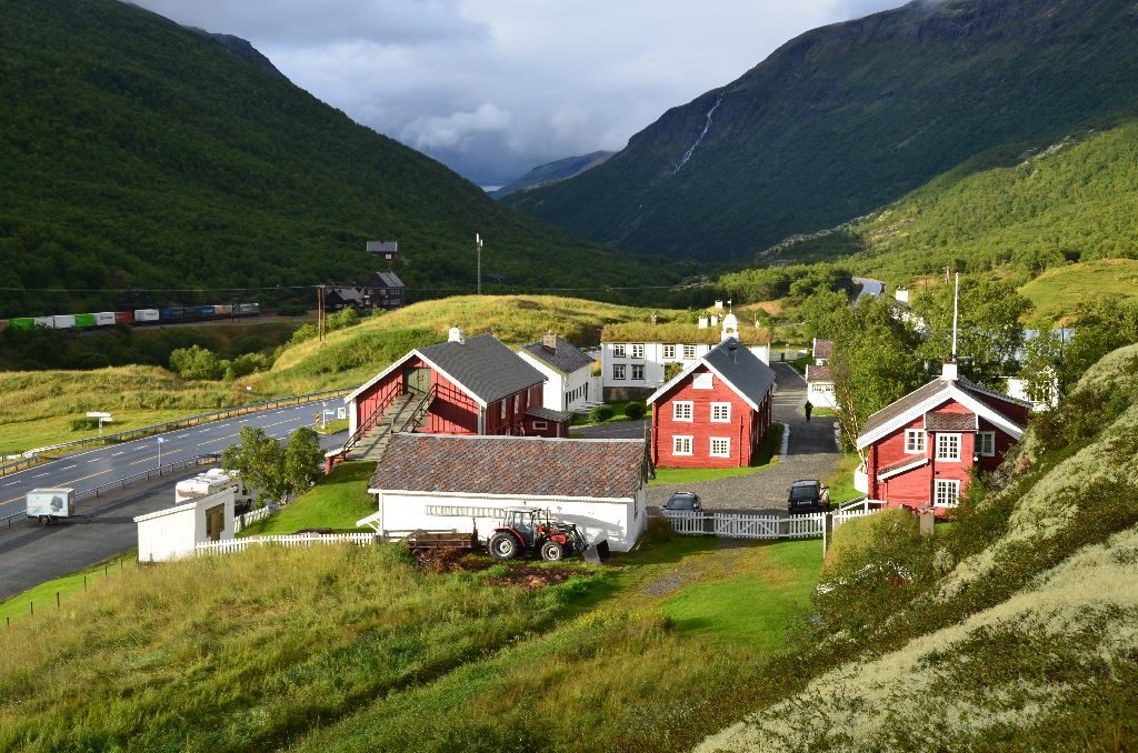 Kongsvold Fjeldstue med hvite 1700-talls trebygninger ved E6 og Dovrefjell i bakgrunnen
