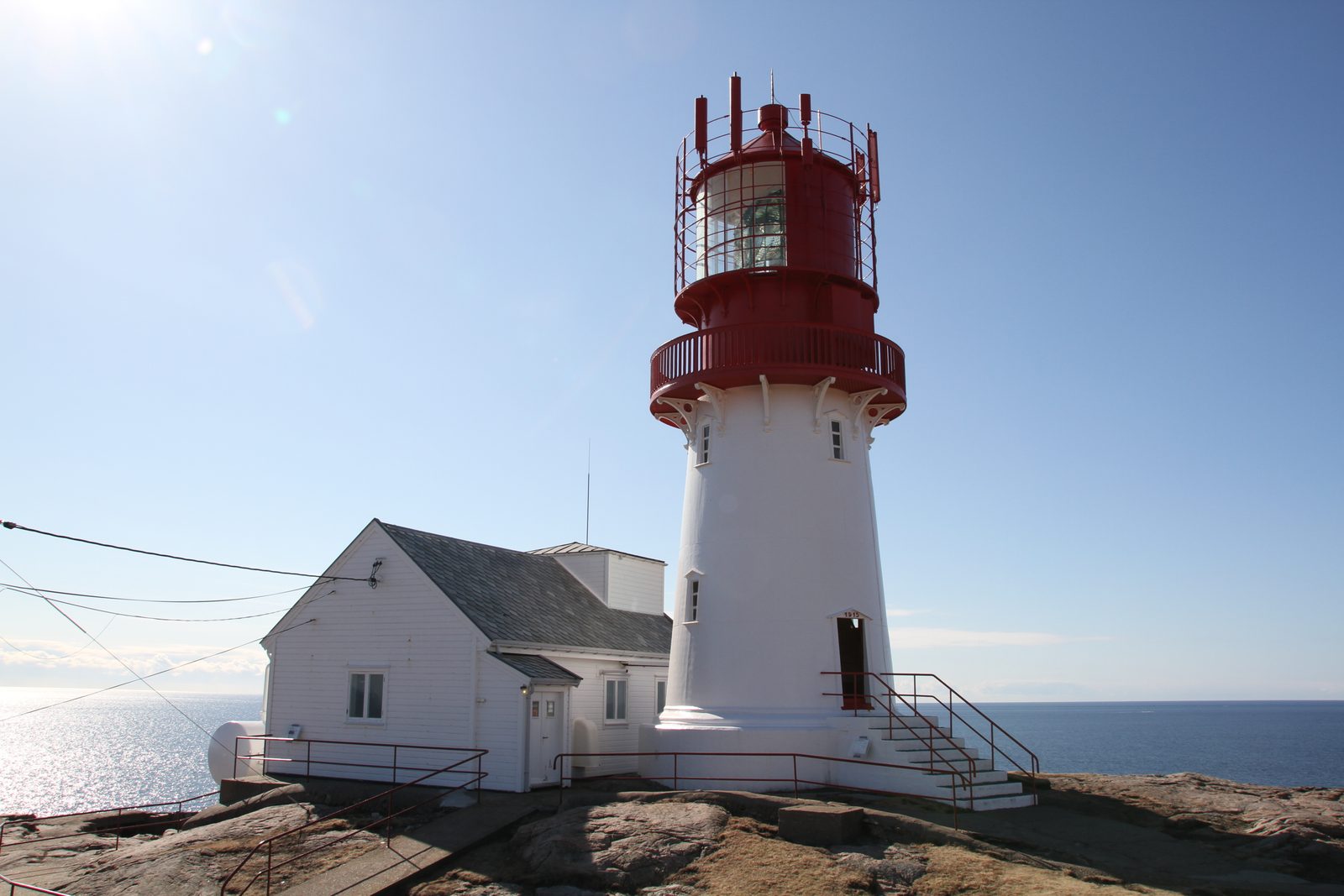 Lindesnes fyr med rød og hvit tårn ved havet på Norges sørligste punkt