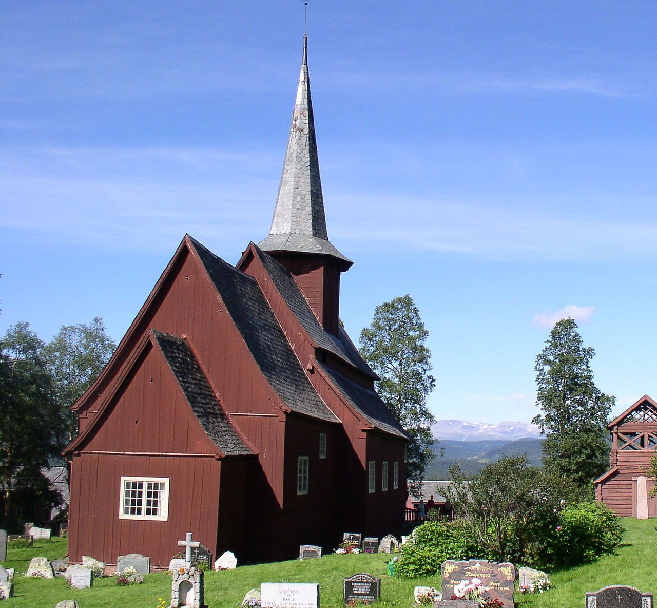 Hegge stavkirke i Øystre Slidre med høyt midtskip og spontak mot Heggefjorden i Valdres