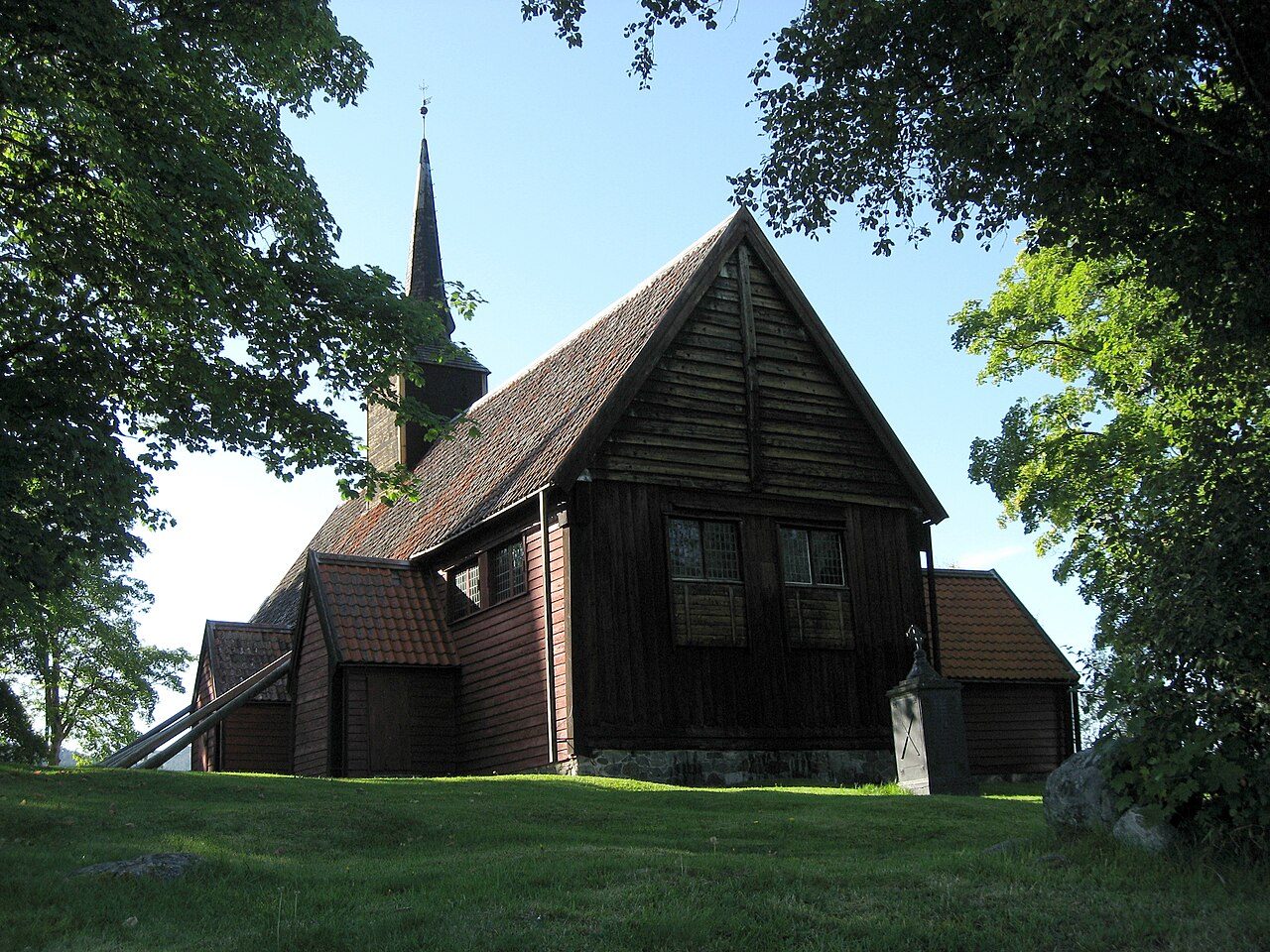 Kvernes stavkirke på Averøy med tjærebredd panel og ytre skråstøtter mot kystlandskap