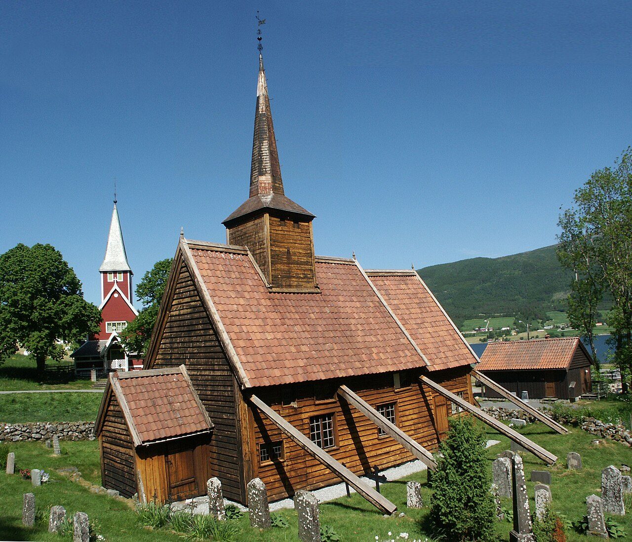 Rødven stavkirke med karakteristiske utvendige skråstøtter mot Romsdalsfjorden