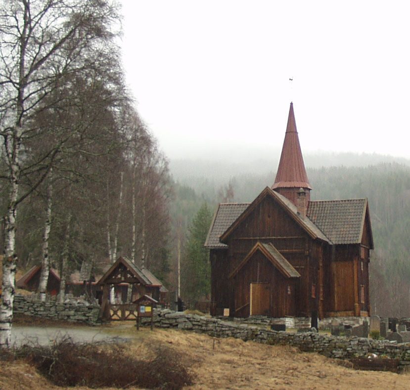 Rollag stavkirke med tjærebredd treverk og korsformet plan på vestsiden av Numedalslågen