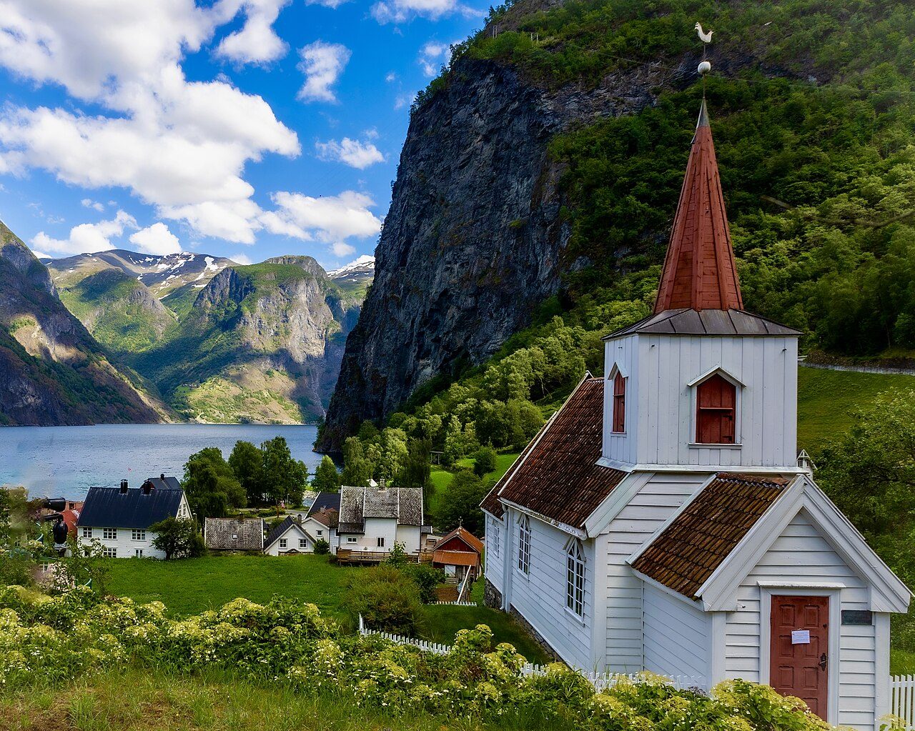 Hvit Undredal stavkirke med tjæret tårn ved Aurlandsfjorden i Vestland