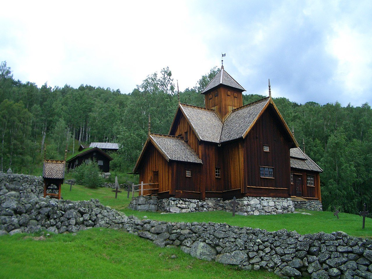 Uvdal stavkirke med svart tjærebredt tretak og hvit takrytter i Numedal