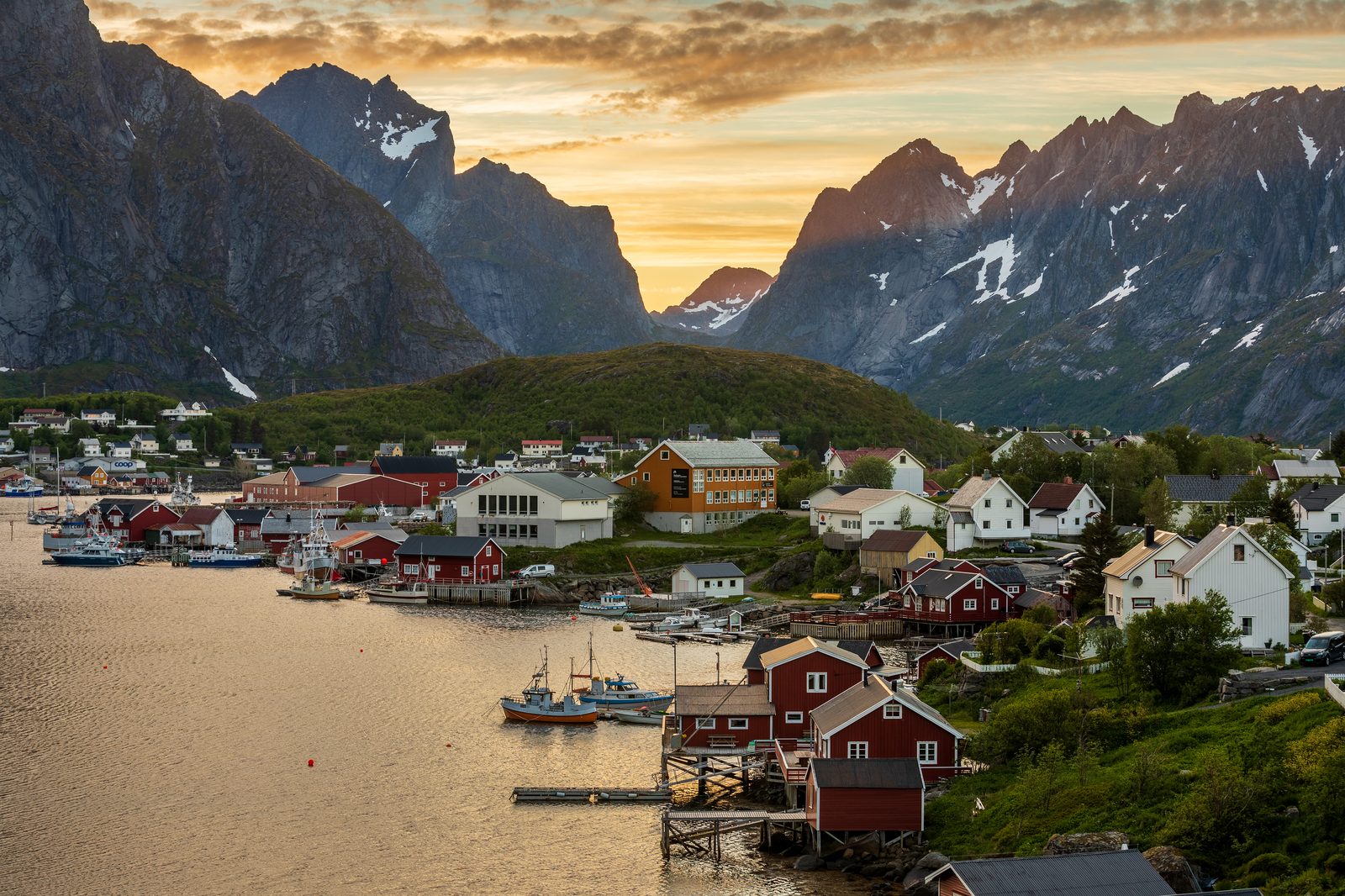 Røde rorbuer i Reine med Reinefjorden og taggete fjell i bakgrunnen