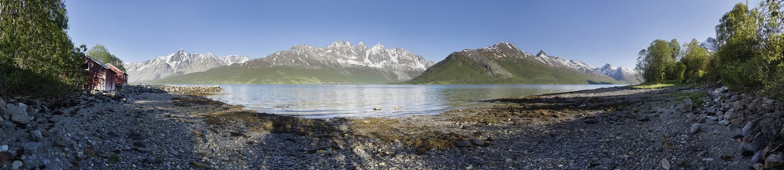 Lyngsalpene speiler seg i Lyngenfjorden med snødekte tinder ned mot sjøen